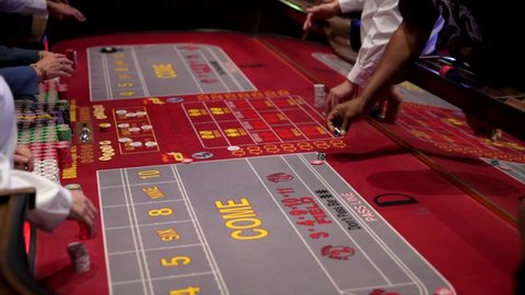This close up video shows a group of people gambling and betting at a craps table in a casino.