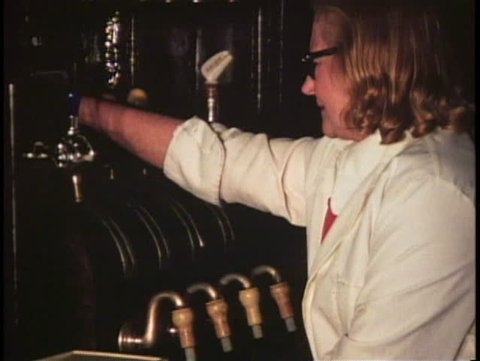 LONDON, ENGLAND, 1976, George Inn, barmaid pulls handles to draw beer, 1970s