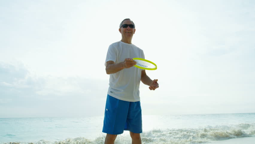 Fit active senior Caucasian man enjoying the ocean waves outdoors in tropical Caribbean destination playing fun games RED WEAPON