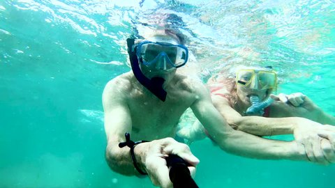 Selfie portrait of active senior Caucasian American couple snorkeling waving to camera making video diary and enjoying Summer adventure Bahamas USA