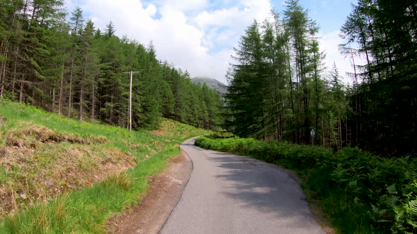 POV drive in Glen Etive mountain forest scenic evergreen pine trees Scottish highland landscape rural valley slopes wilderness Scotland UK Europe 