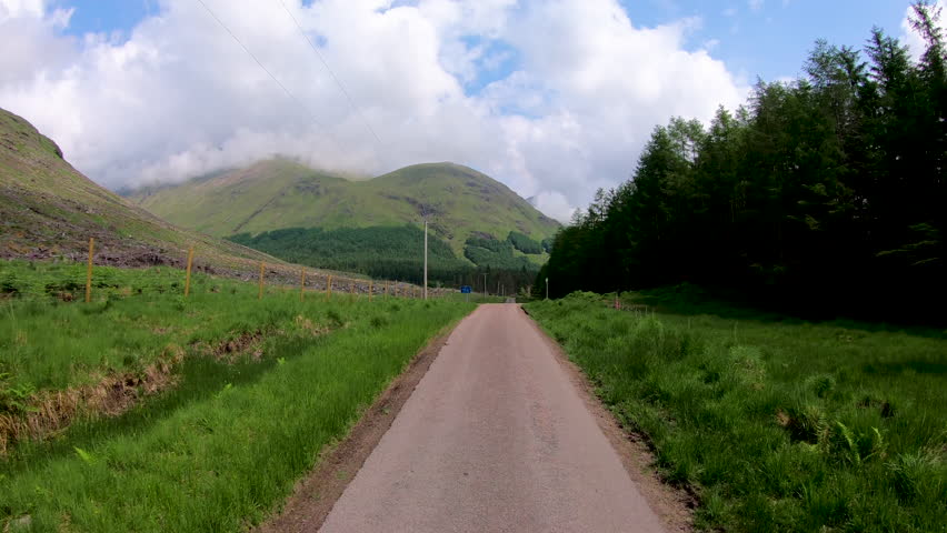 POV scenic driving in Glen Etive Scottish highland landscape mountain slopes rural evergreen forest valley wilderness Scotland UK Europe 