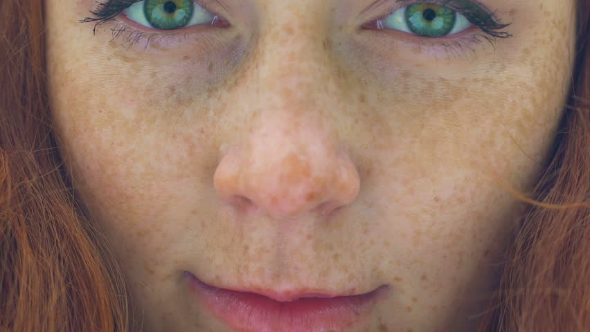 Beautiful red haired girl with freckles and green eyes extreme close up, slow