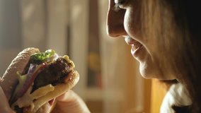 brunette woman sniffing and eating big burger