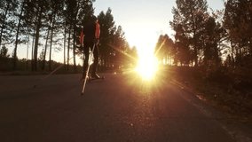 Training an athlete on the roller skaters. Biathlon ride on the roller skis with ski poles, in the helmet. Autumn workout. Roller sport. Adult man riding on skates. Shooting action cam. Slow motion.