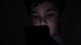 Closeup of Young Happy Boy Face looking at Smartphone at Night at Home