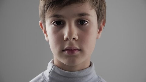 Close up Portrait of cute young 11 - 12 year old boy looking at the camera on white background