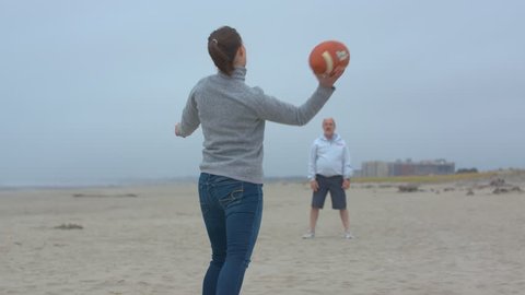 Father and Daughter Playing Catch with a Football on a Cold Day at the Oregon Coast Arkivvideo