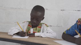 Black native African boy in a school in a village in rural Africa. 4K RAW clip, please modify and edit (color grade, stabilize, etc.) in postproduction.