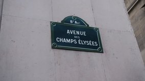 Classic street sign of Avenue Champs Elysees or Elysian Fields located on a house in Paris. France. Shot with parallax effect relative to houses in the background. Illustration of shopping and