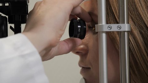 Doctor looks at the patient's eyes with a beam of light and a magnifying glass