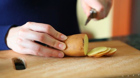 Woman hands cutting potatoes on wooden board on the kitchen