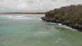 4K aerial drone video of volcanic rocks on the beach, waves crashing on rocks. Bali island.