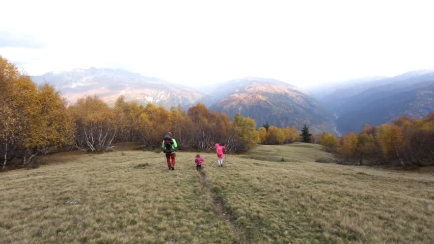Family trekking in the mountains of Georgia. Golden autumn. Yellow leaves. Dad and two daughters. Fantastic view.