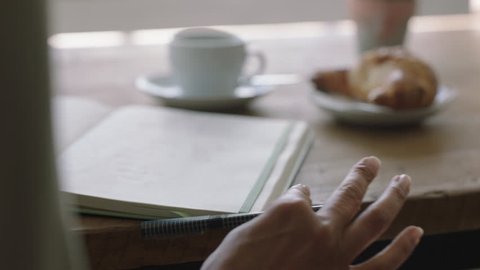 young woman hands writing to do list making notes in diary planning using journal reminder in coffee shop close up