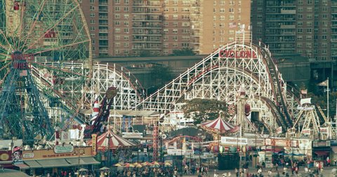 Coney Island, New York CIRCA - September 2018. Aerial view of roller coasters and ferris wheel at amusement park  New York City, bright day lighting. Close to Wide shot on 4k RED camera.
