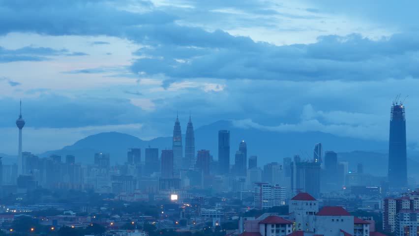 Kuala Lumpur City skyline basking under the warm glow of golden light and beautiful rays during sunset with low clouds moving in the background. Wide angle shot