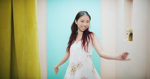 Fashionable female opening curtain to dressing room and showing off her dress in interior boutique clothing store with bright lighting. Medium shot on 4k RED camera. 