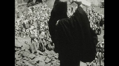 1930s: Moses smashes stone tablets on ground. Crowd recoils in shame. Men and woman hold out their fists and kneel.