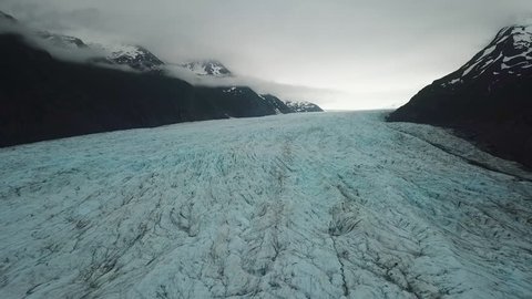 Aerial View of Glacier Ice Between Dark Mountains