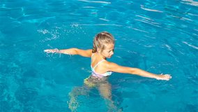 Adorable little girl having fun in outdoor swimming pool. SLOW MOTION VIDEO