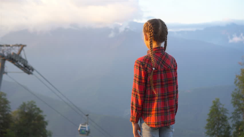 Adorable happy little girl in mountains in the background of beautful landscape