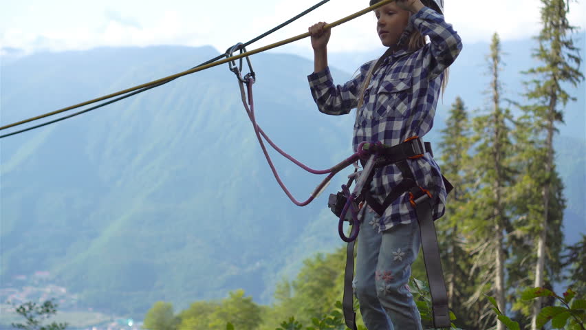The rope bridge on the top of mountain of Rosa Khutor, Russia. Little brave kid on a pendant bridge over an abyss in the mountains