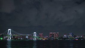 Night timelapse of Tokyo's Rainbow bridge with rolling clouds.