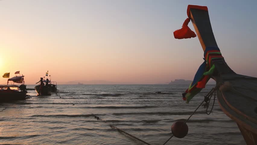 Krabi beach Ao Nang in Thailand, traditional boats at sunset.