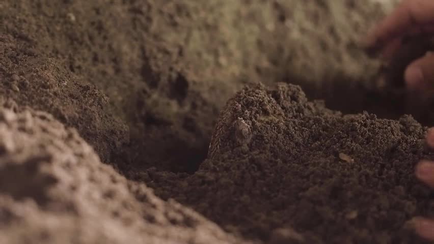 A man like Jesus Christ is digging a hole in the dungeon, a man is searching for a precious treasure, a man in a white robe is digging the earth with a stick and finds gold, Jesus hides the holy grail Royalty-Free Stock Footage #1018537807