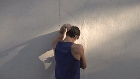 man does active physical exercises against a wall in a morning park. Age forty years.