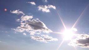 Sun rays shining in white clouds & clear blue sky, beautiful weather, time lapse cloudscape in horizon, panoramic view.