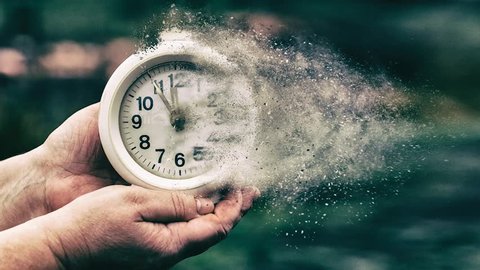 Time is running out concept shows clock that is dissolving away into little particles. Retro vintage alarm clock in old hand.
