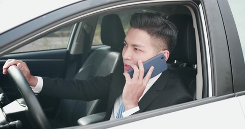 business man speaks on phone happily in the car