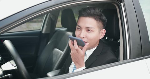 business man sends audio message by smart phone in the car