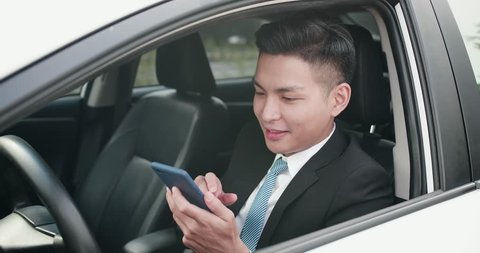 business man uses a phone happily in the car
