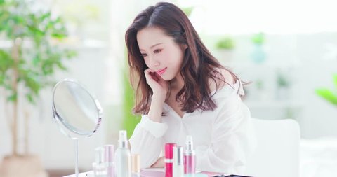 woman make up and looks mirror at home