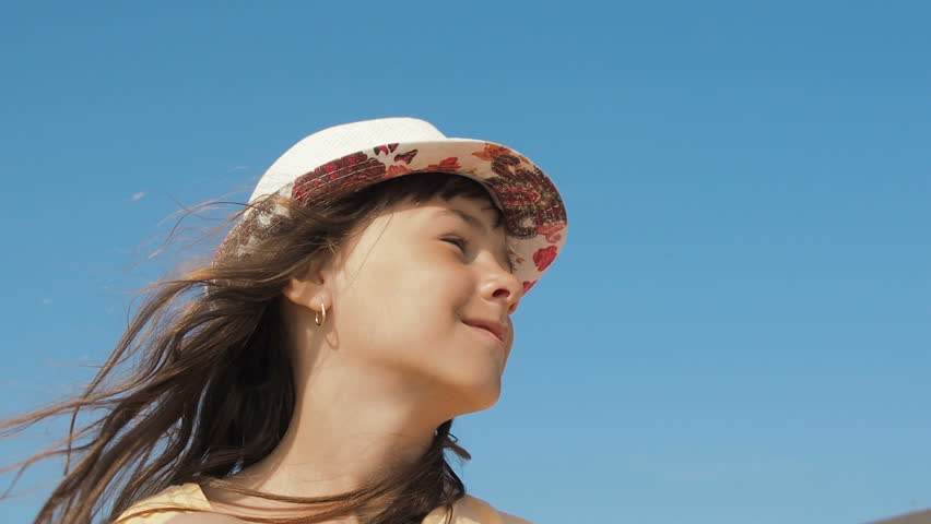 Portrait of a happy against the sky. Little girl in a hat on vacation.