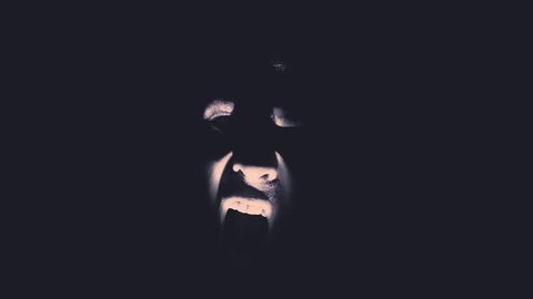 A scary face emerges from the darkness.