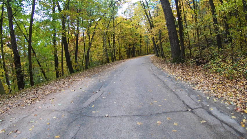 Driving on colorful winding Autumn forest road through Devil