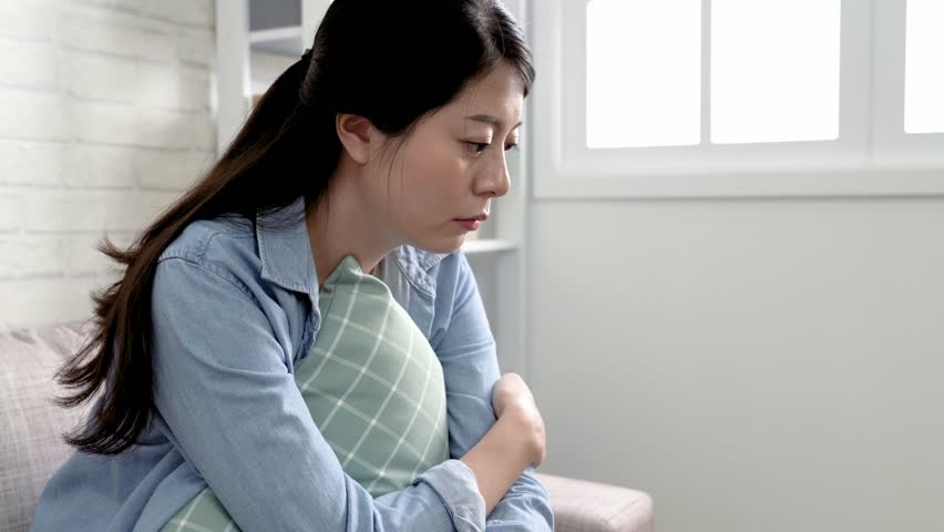 Asian woman broke up with boyfriend and heart broken crying loudly. young girl sitting on the couch covering her face with hands because of sadness. Sad lady sitting on a sofa in the living room. | Shutterstock HD Video #1018585678