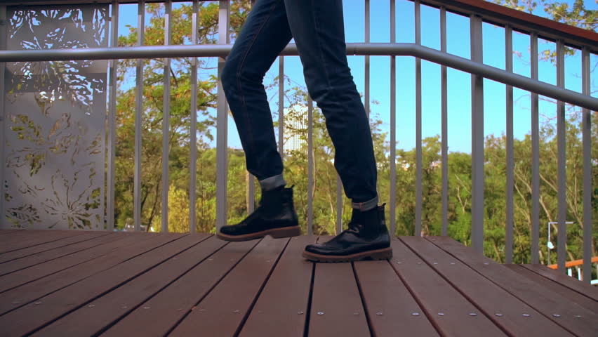 Side view man climbs the stairs slow motion. close up details male legs wearing jeans and trendy shoes outdoors