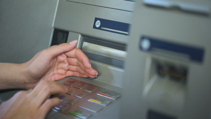 Lady hiding keyboard of automated teller machine while inserting her pin code | Shutterstock HD Video #1018596556