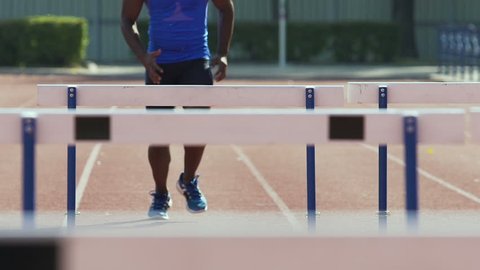 Athlete running hurdle race, tempering strength and endurance in competition