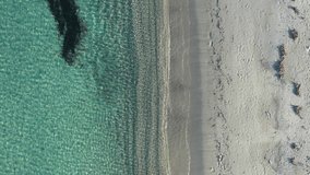 Video from above, aerial view of a beautiful white beach bathed by a clear and transparent sea. Sardinia, Italy.