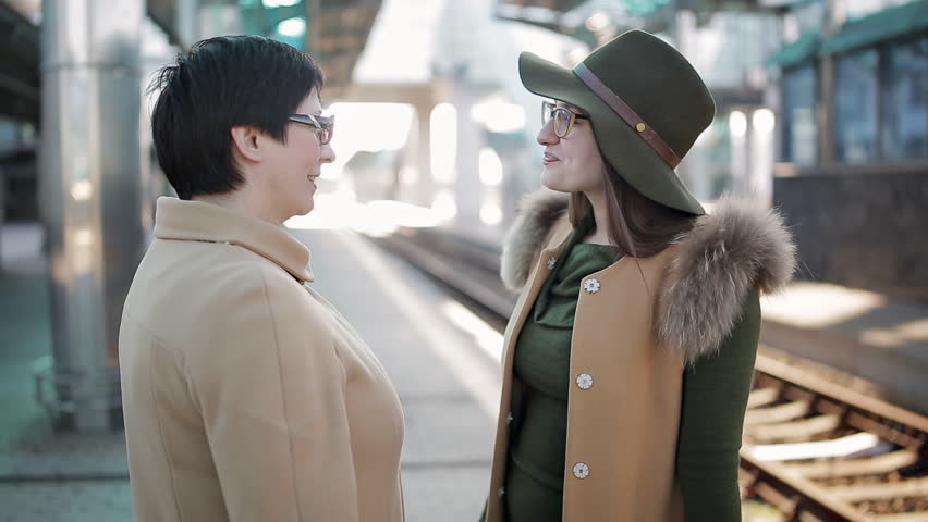 Adult woman escorts his daughter on the platform of the railway station.