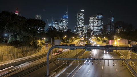 Night scene time lapse of traffic light trail to Sydney city skyline. Pan right