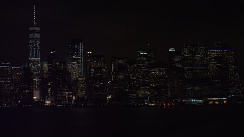 Aerial pan of Manhattan skyline with buildings and skyscrapers and river, New York City, with dark night lighting. Wide shot on 4k RED camera.