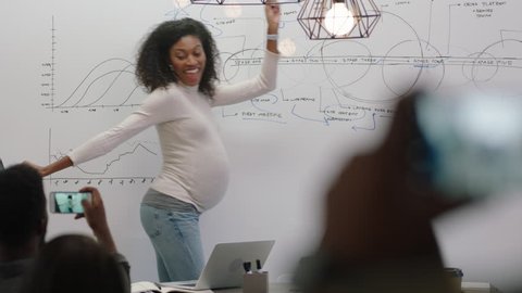 successful pregnant business woman celebrating success african american team leader dancing funny excited colleagues clapping enjoying corporate victory in boardroom meeting