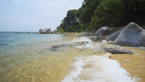 Gentle waves wash over and between boulders on this exotic. tropical beach paradise. Thailand. 4k video with sounds